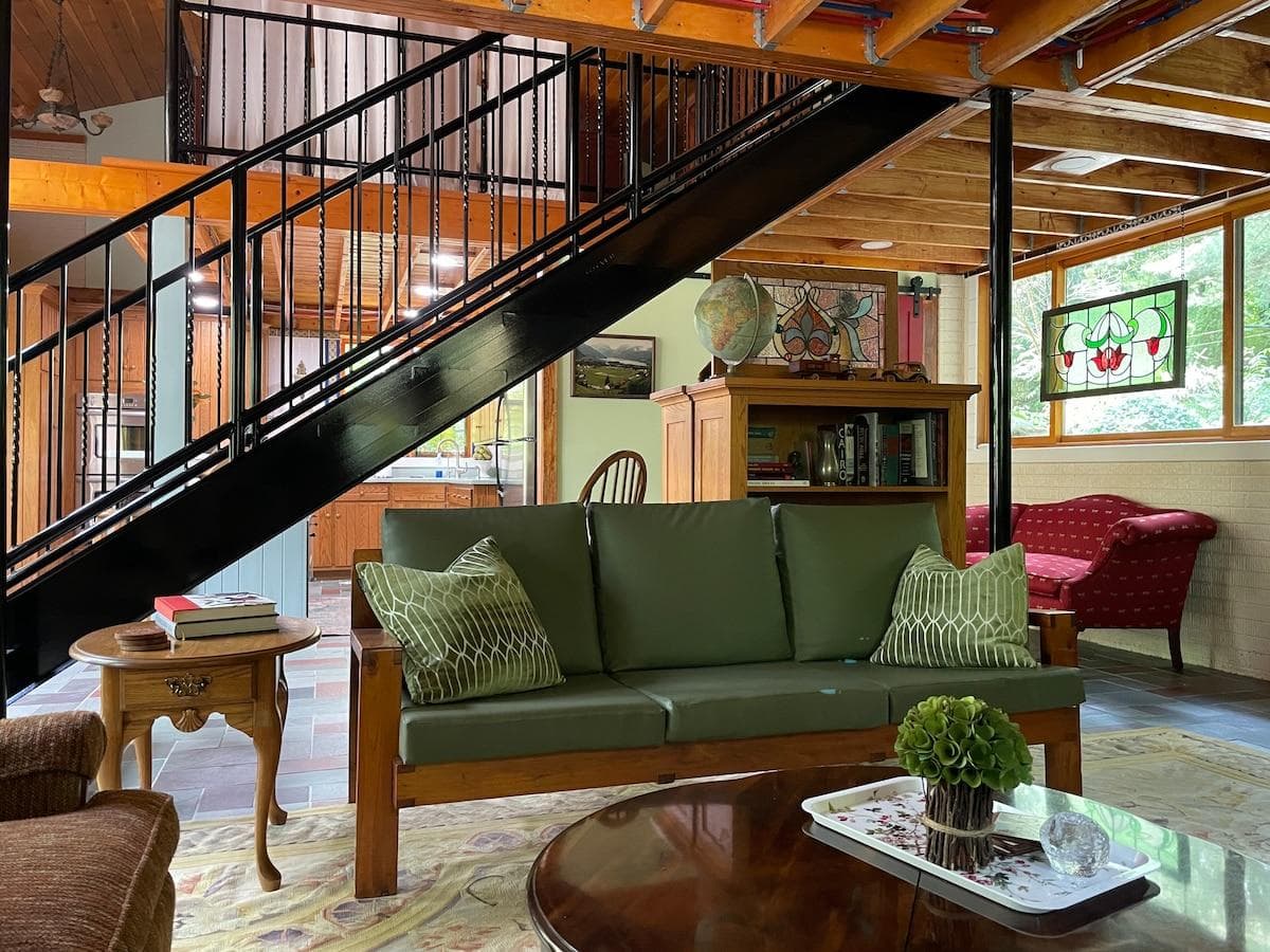 Open floor plan living room area w kitchen visible on other side of stairwell to loft
